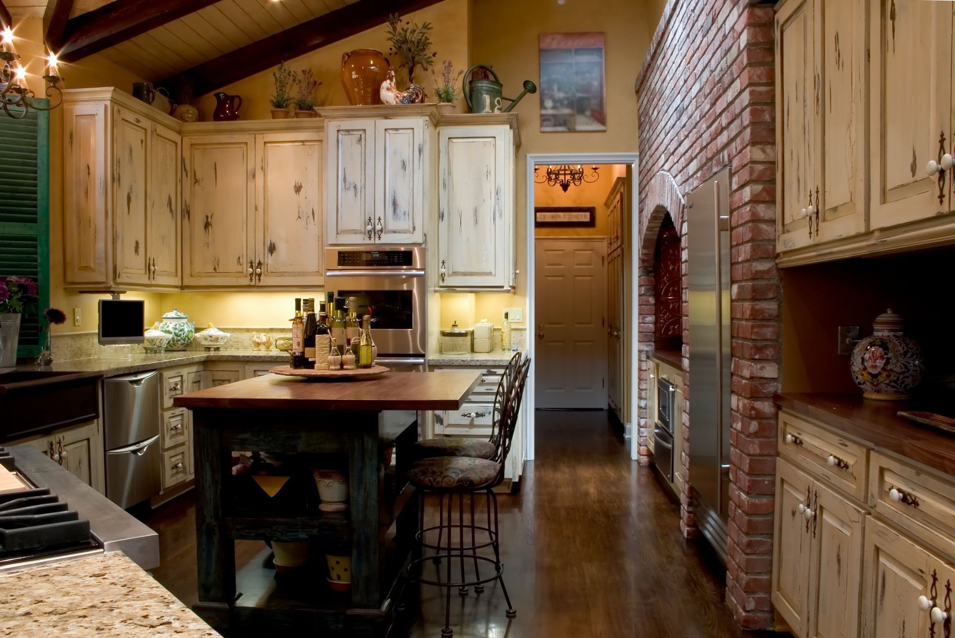 Rustic kitchen with wood cabinets, brick wall, island, and stainless steel appliances