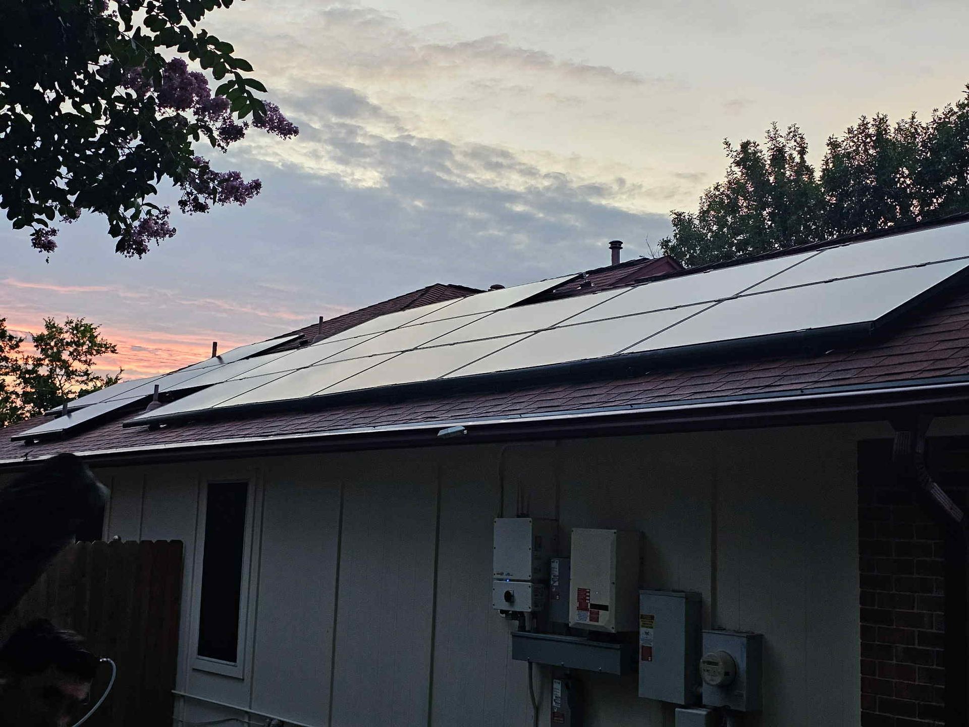 Solar panels on a residential roof against a sunset sky.