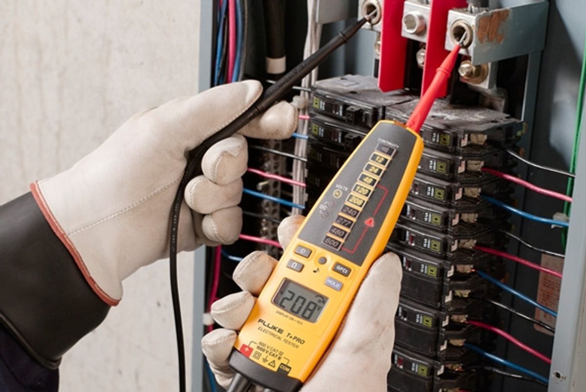 A person is holding a digital multimeter in their hand.