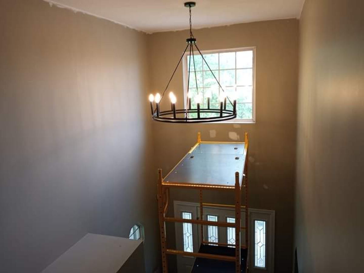 A chandelier is hanging from the ceiling above a scaffolding in a room.
