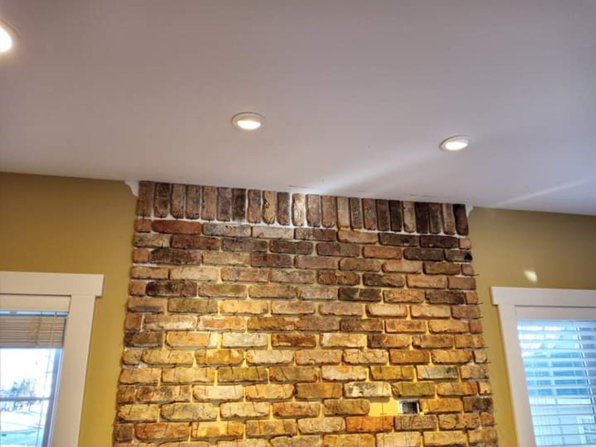 A living room with a fireplace and a brick wall.