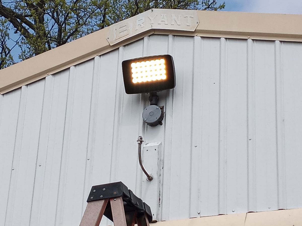A ladder is sitting next to a light on the side of a building.