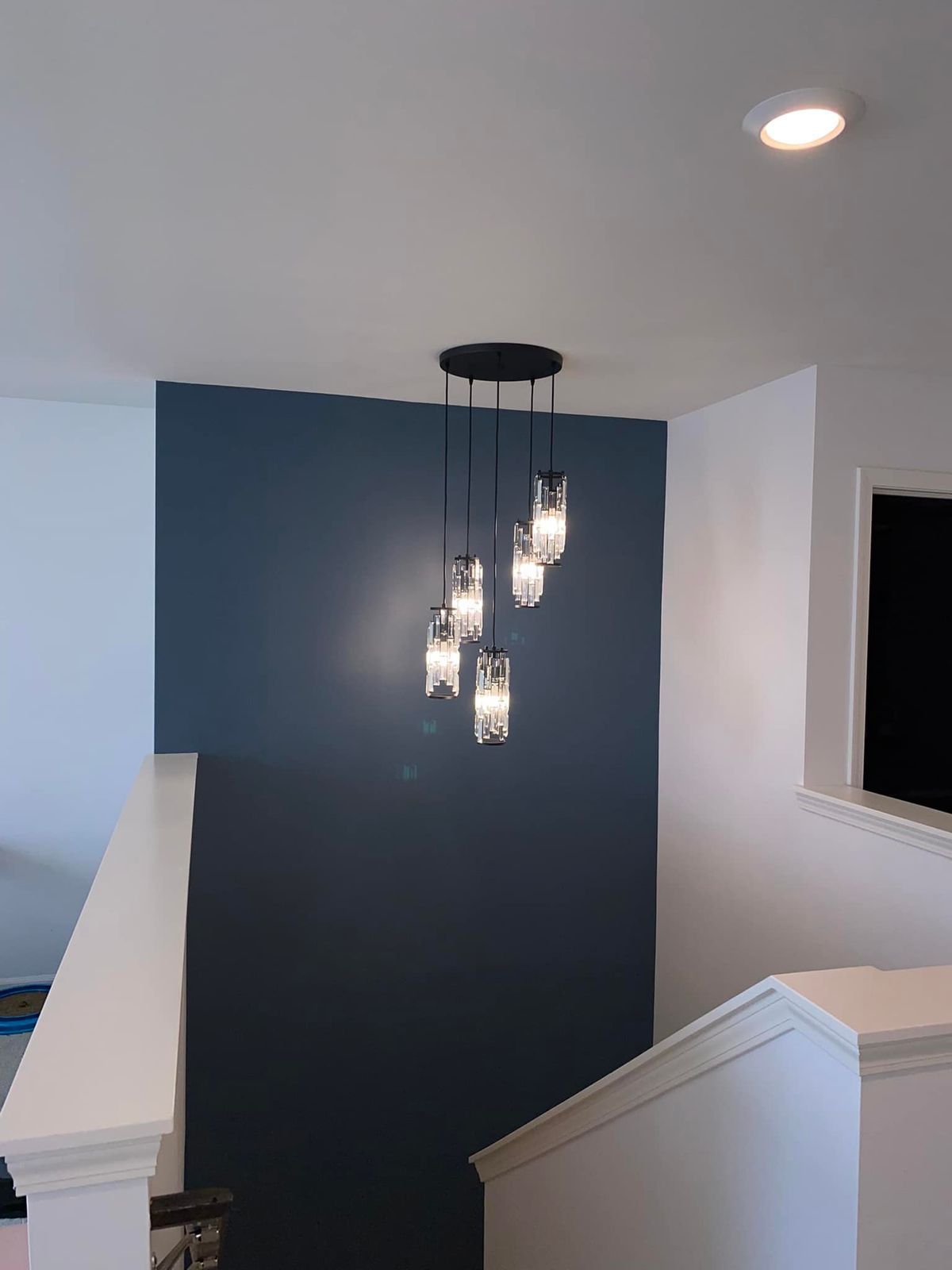 A staircase with a blue wall and a light hanging from the ceiling