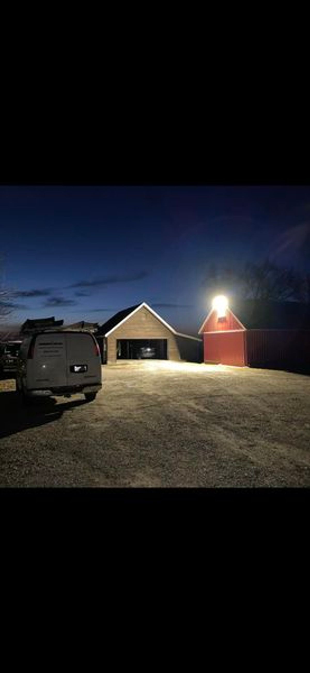 A truck is parked in front of a barn at night.