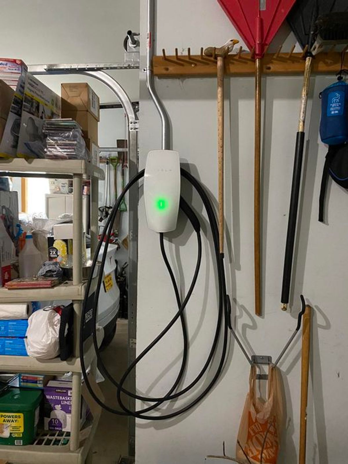 A charging station is hanging on a wall in a garage.