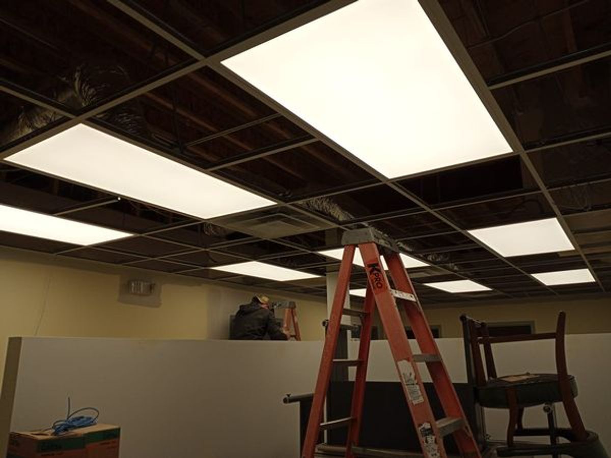 A ladder is sitting under a ceiling with lights on it.