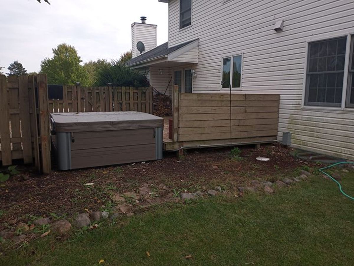 A hot tub is sitting in the backyard of a house.