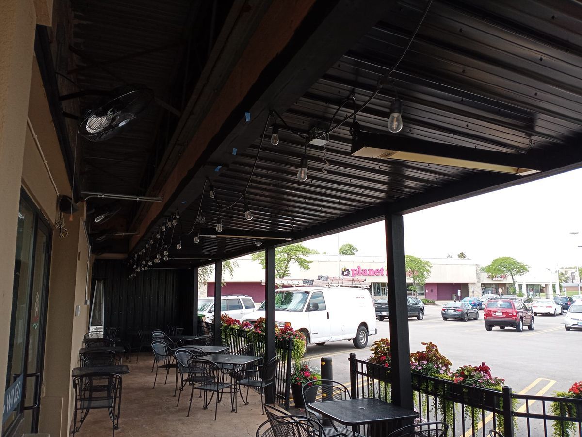 A restaurant with tables and chairs under a canopy