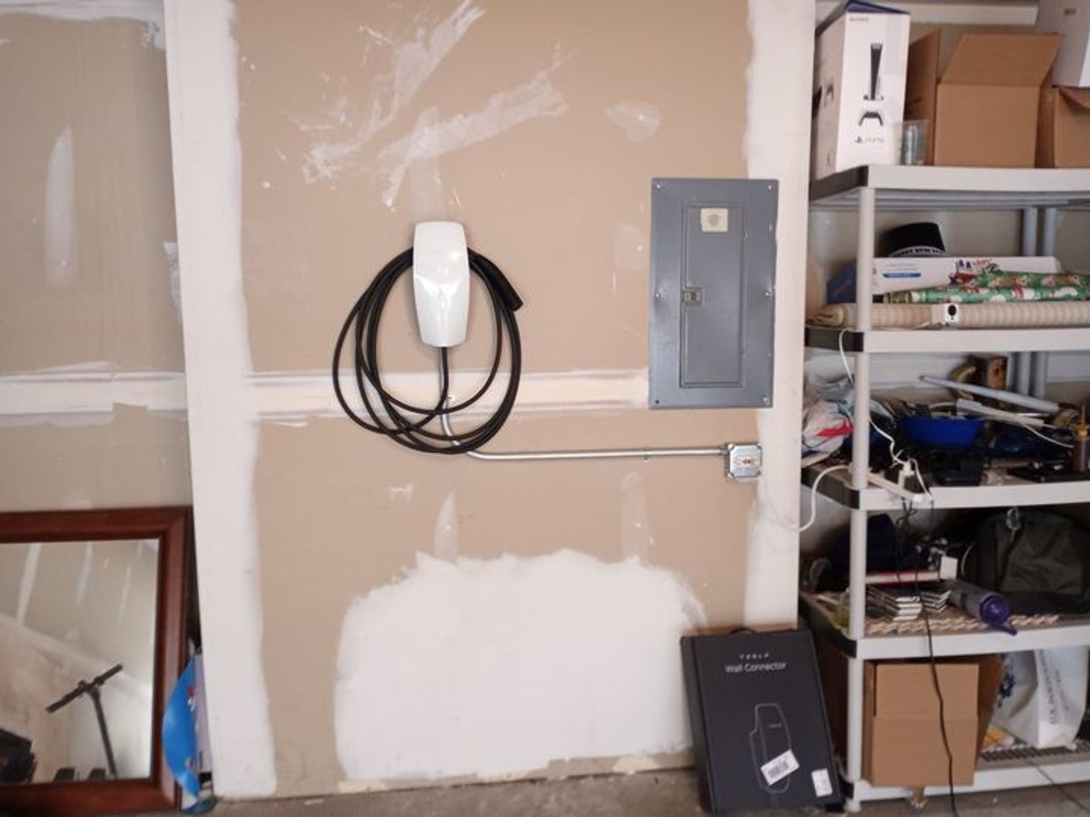 A tesla charging station is hanging on a wall in a garage
