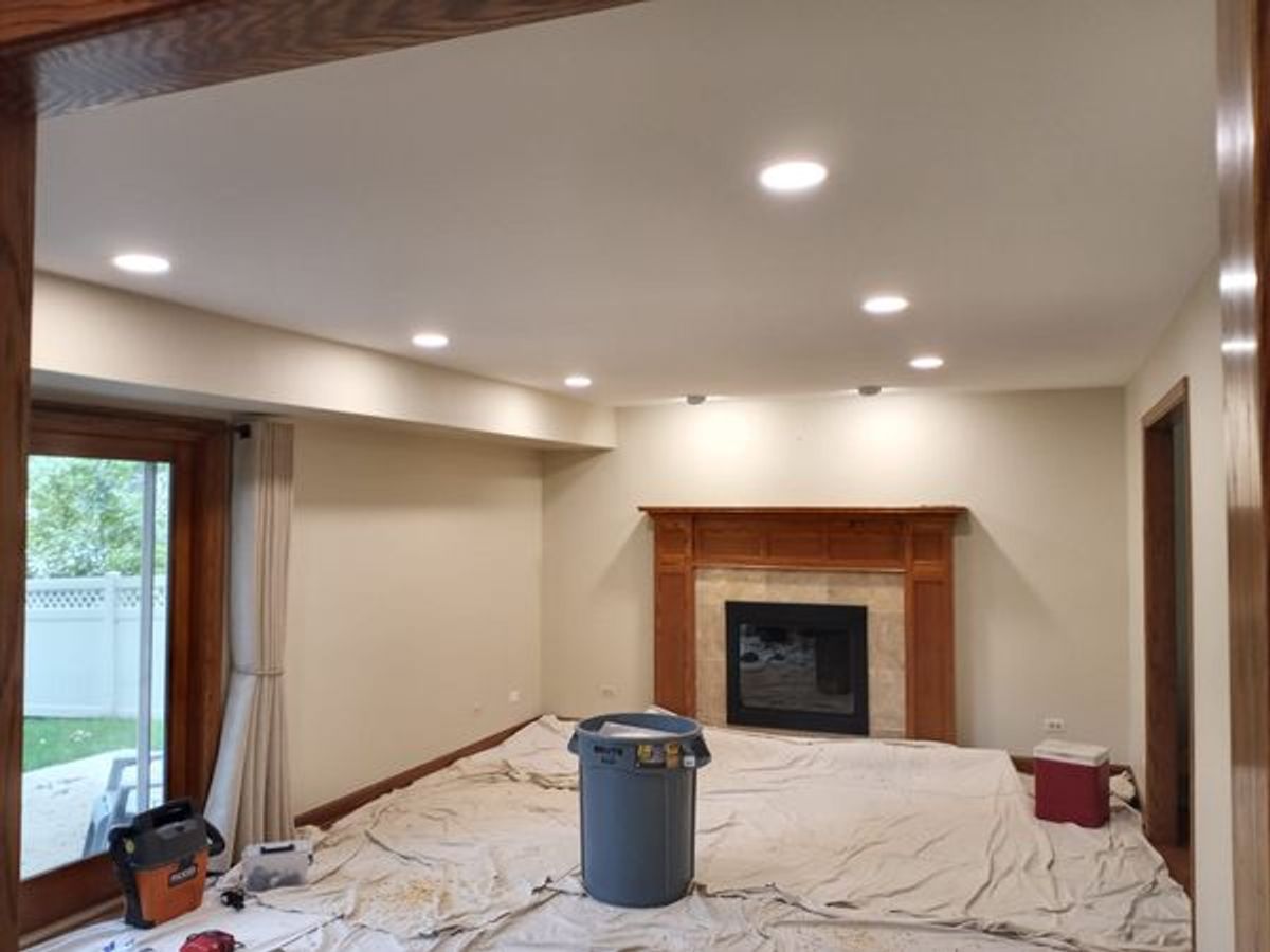 A living room with a fireplace and a trash can on the floor.
