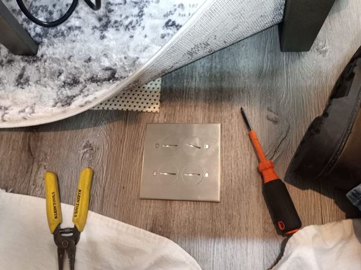 A pair of pliers and a screwdriver are sitting on a wooden table.