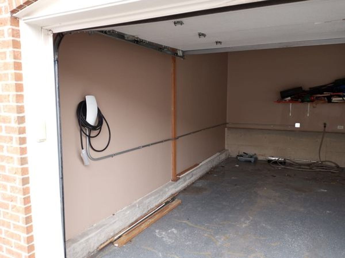A tesla charging station is mounted on the wall of a garage