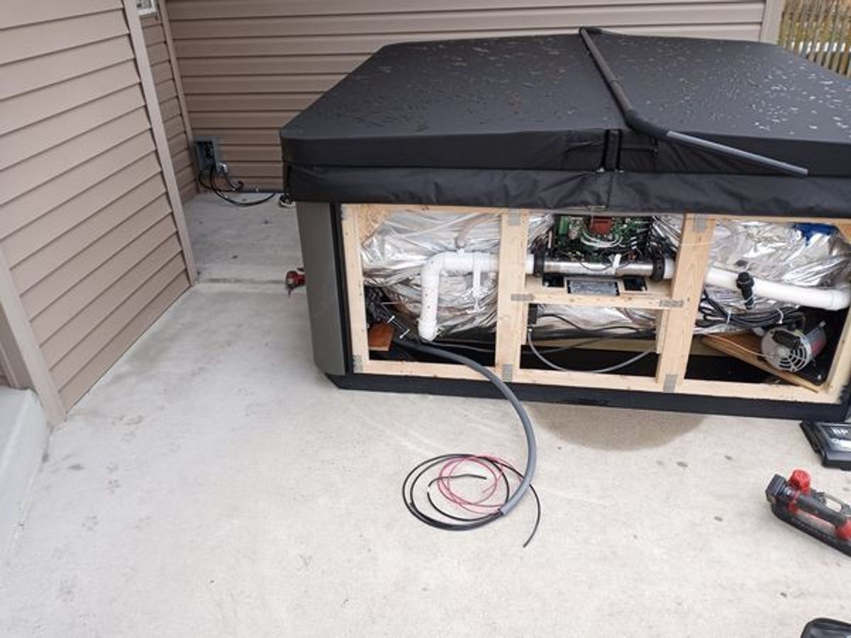 A hot tub with a black cover is sitting on a concrete floor.