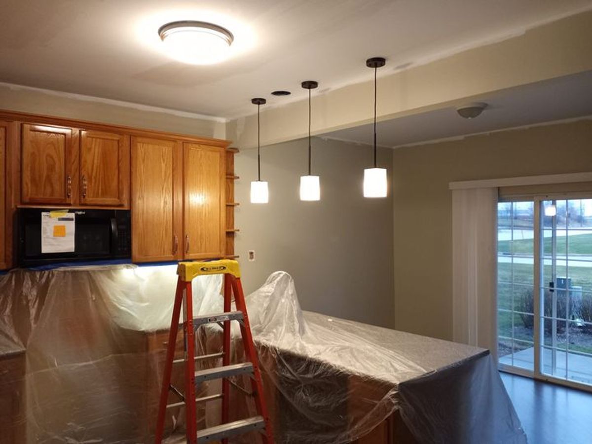 A kitchen with a ladder in the middle of it