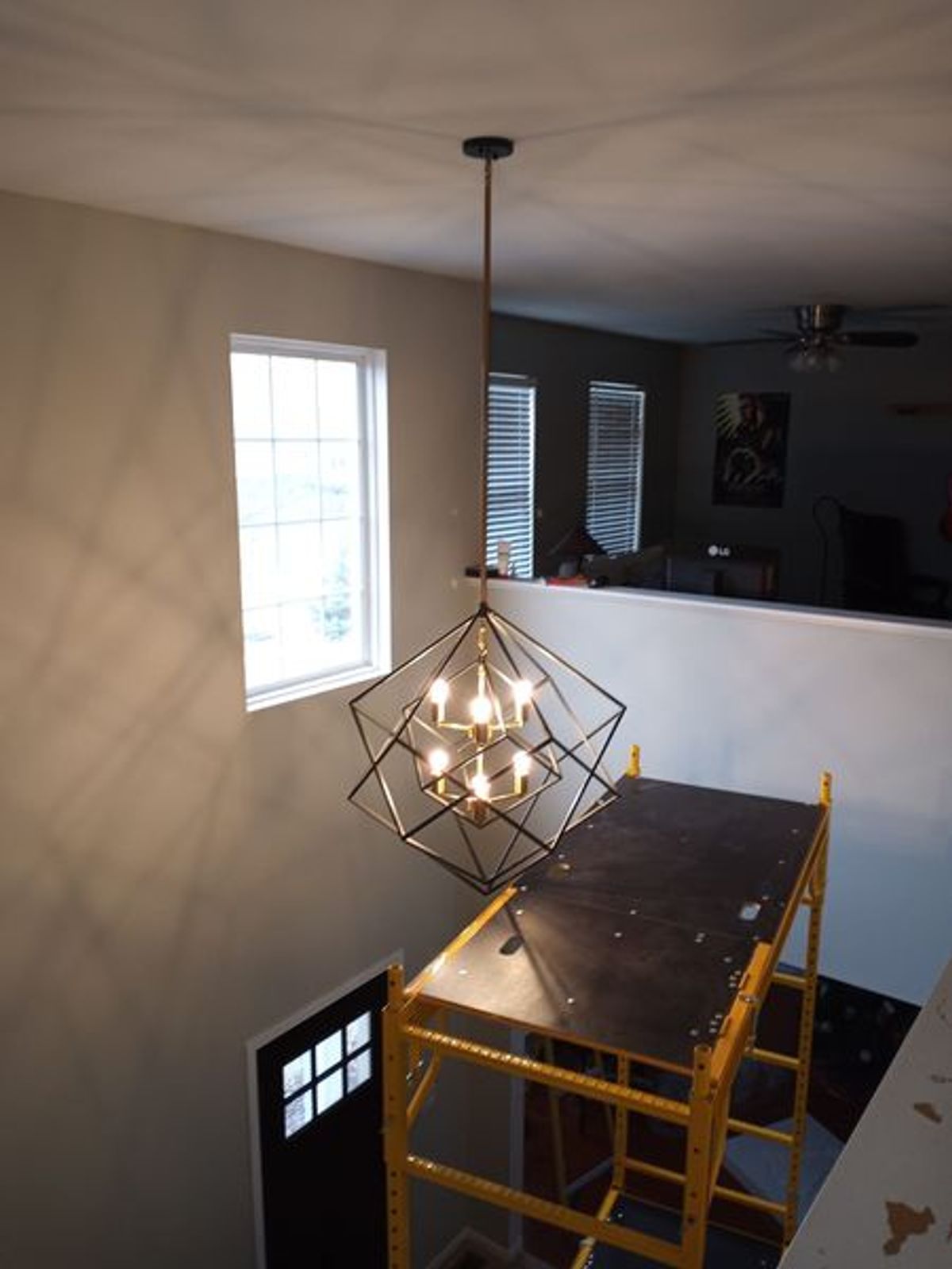 A chandelier is hanging from the ceiling above a table in a room.