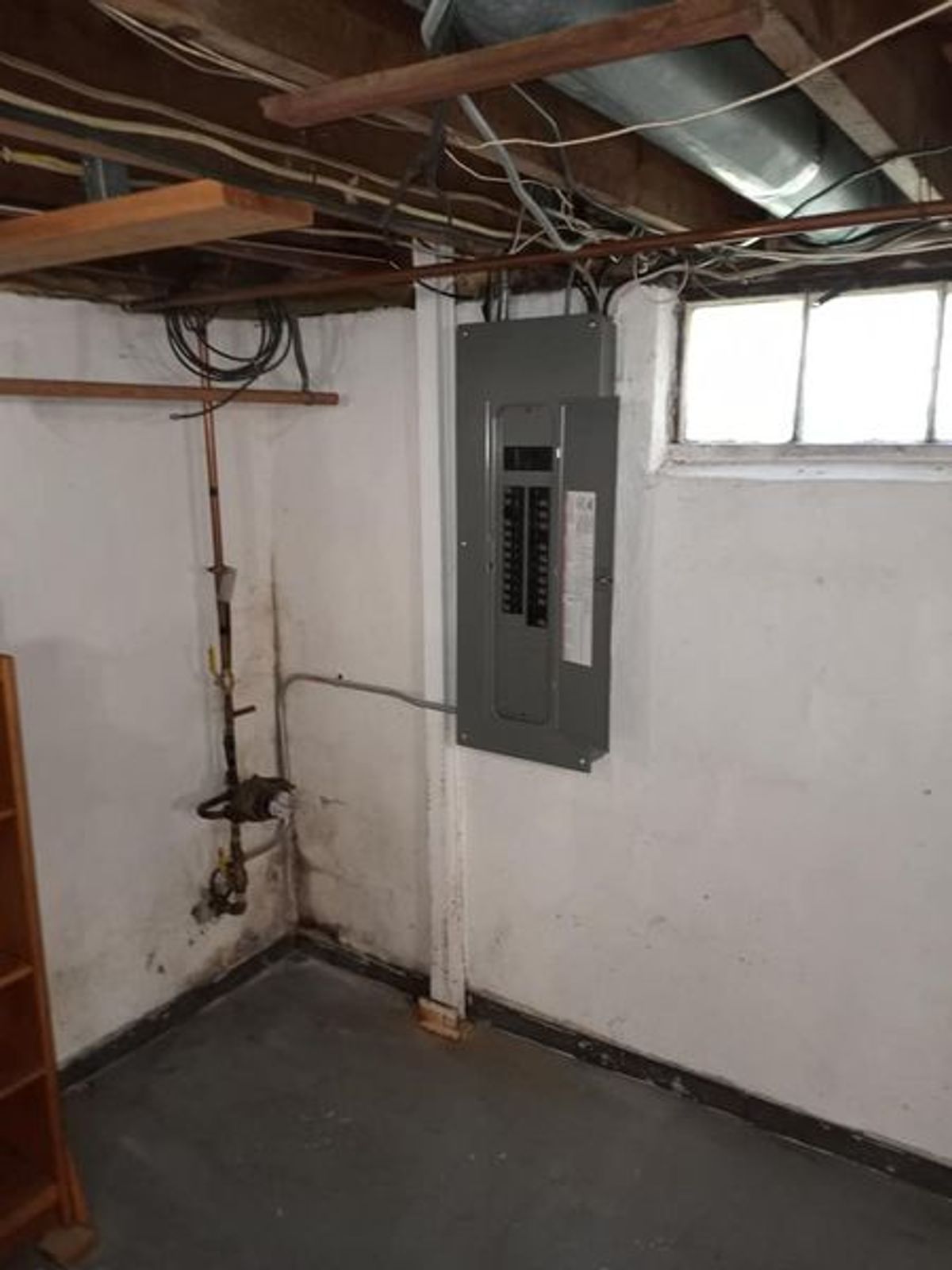 A room with a electrical box on the wall and a window.