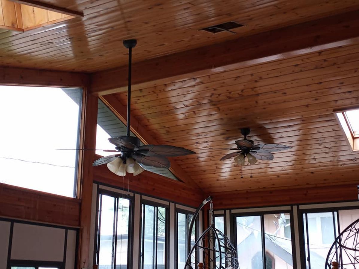 A ceiling fan is hanging from the ceiling of a room with lots of windows.