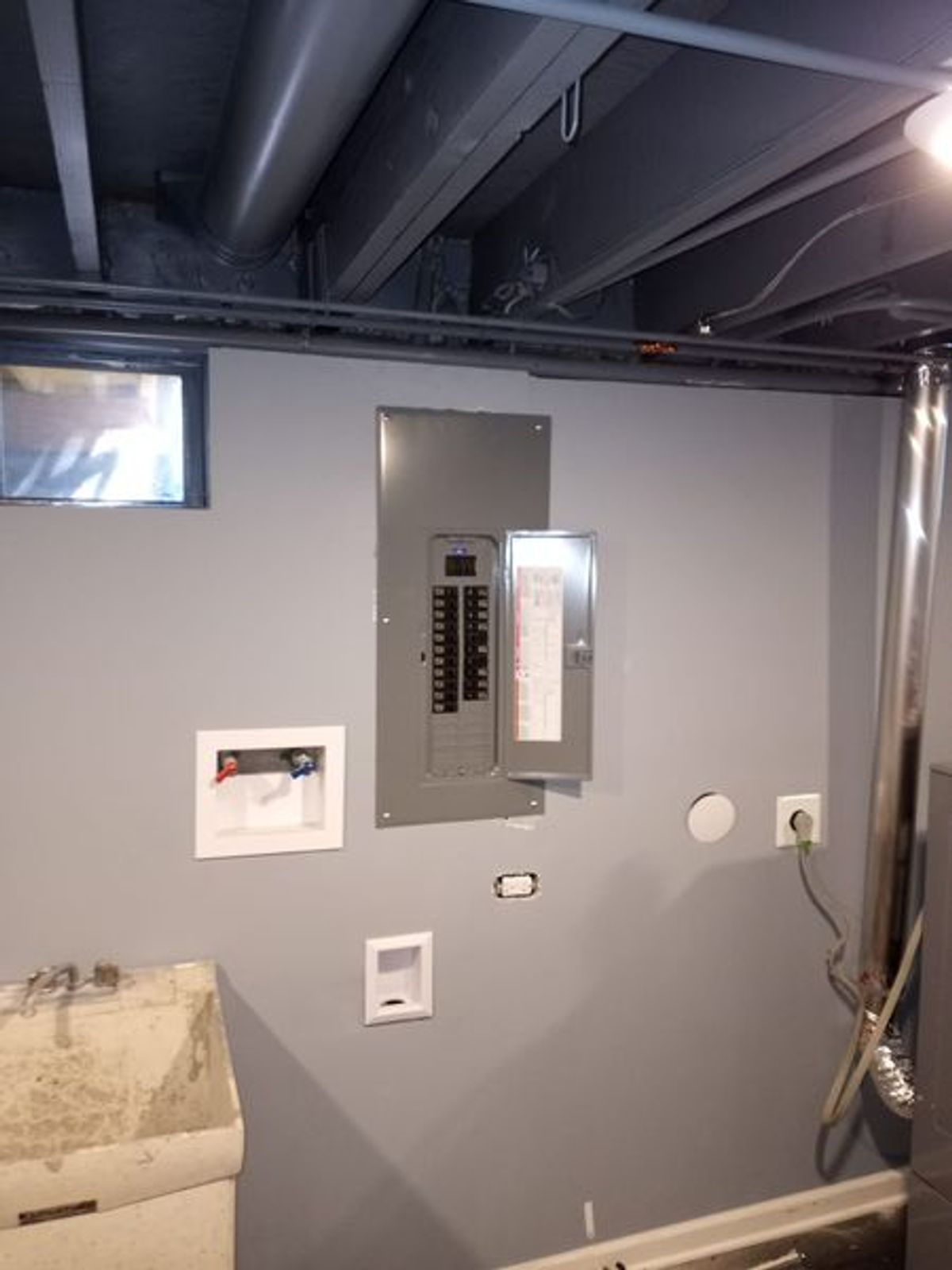 A bathroom with a sink and a electrical box on the wall