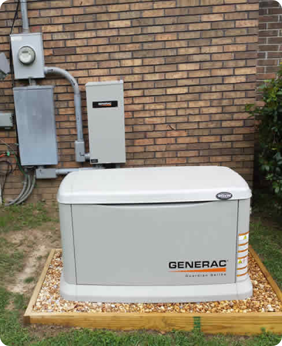 A generator is sitting in front of a brick wall.