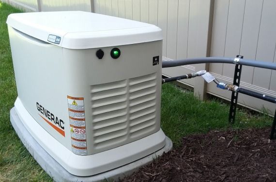 A generator is sitting in the grass next to a fence