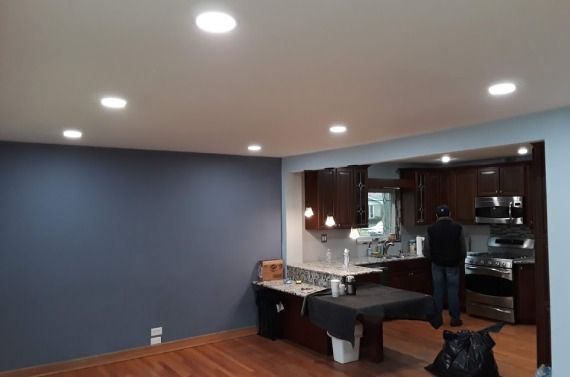 A man is standing in a living room next to a kitchen.
