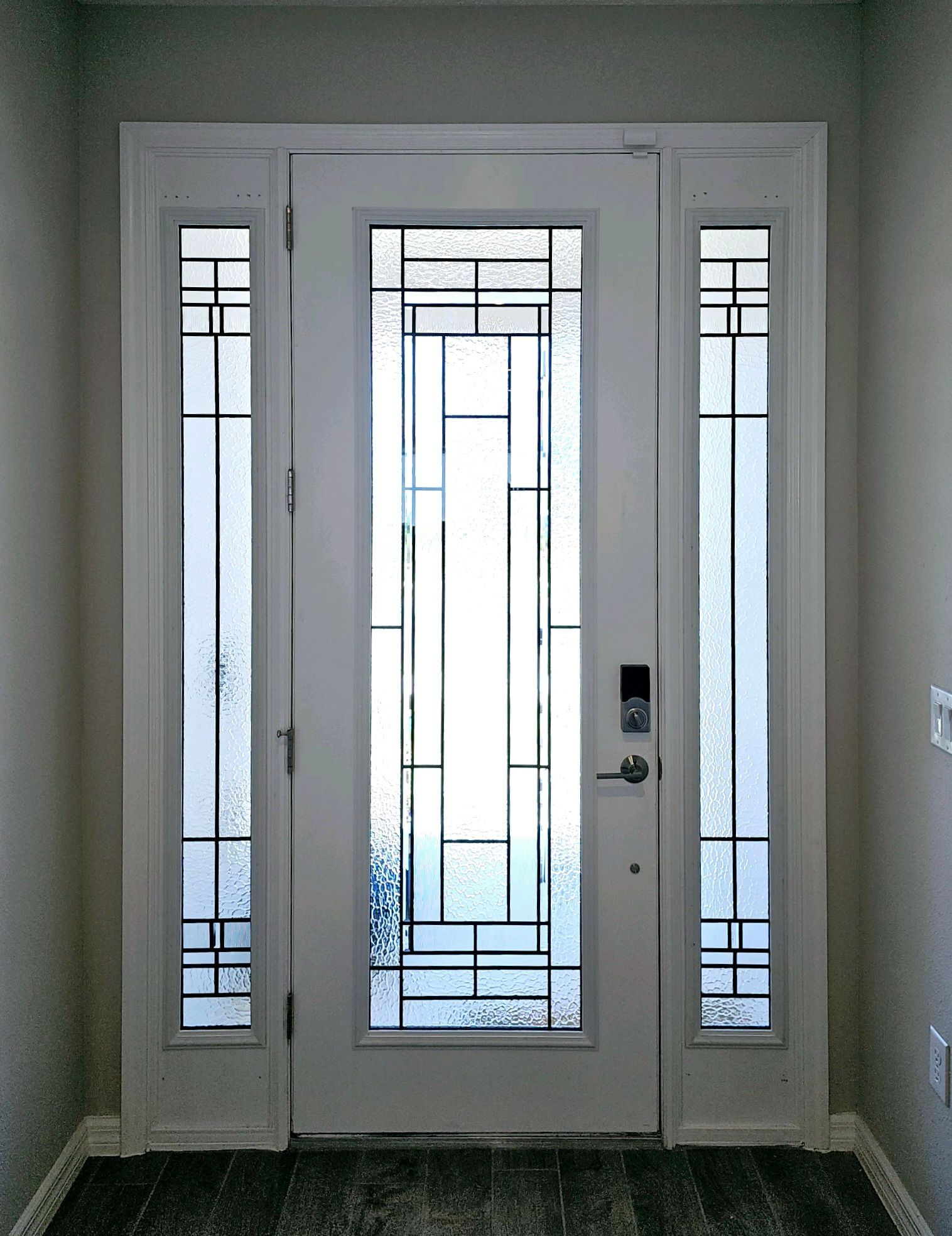 White front door with glass panels and sidelights, modern design.