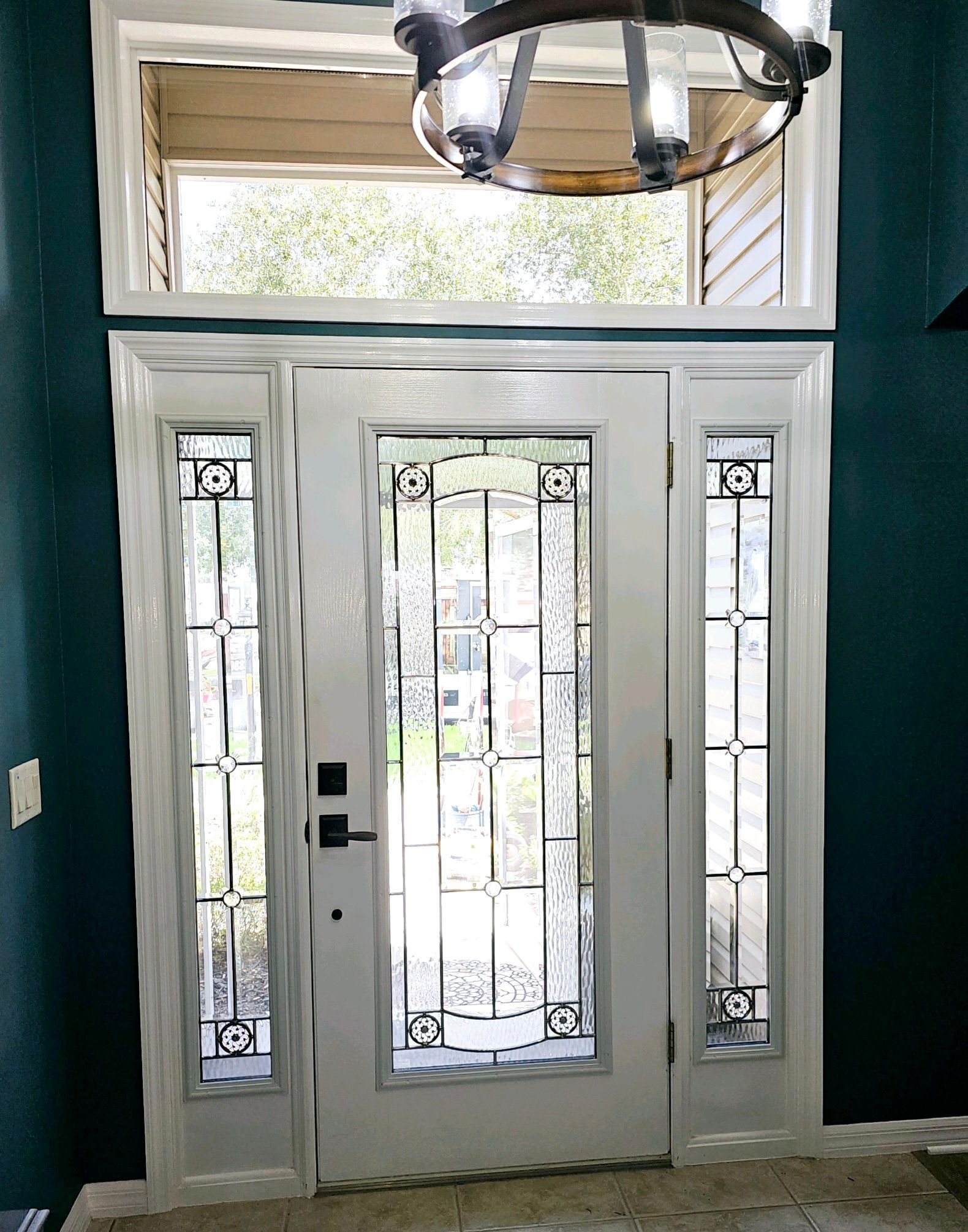White front door with sidelights and transom window; teal wall.