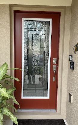 Red front door with frosted glass panel and white trim.