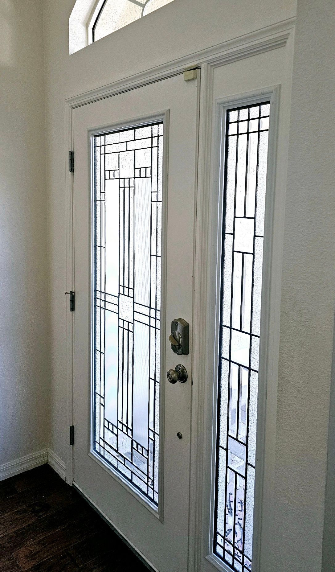 White front door with decorative glass panels and a sidelight.