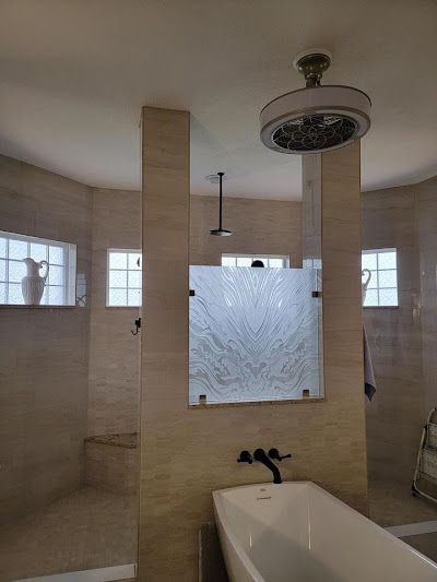 Spacious bathroom with glass shower wall, bathtub, and ceiling-mounted showerhead. Beige tile and neutral color palette.