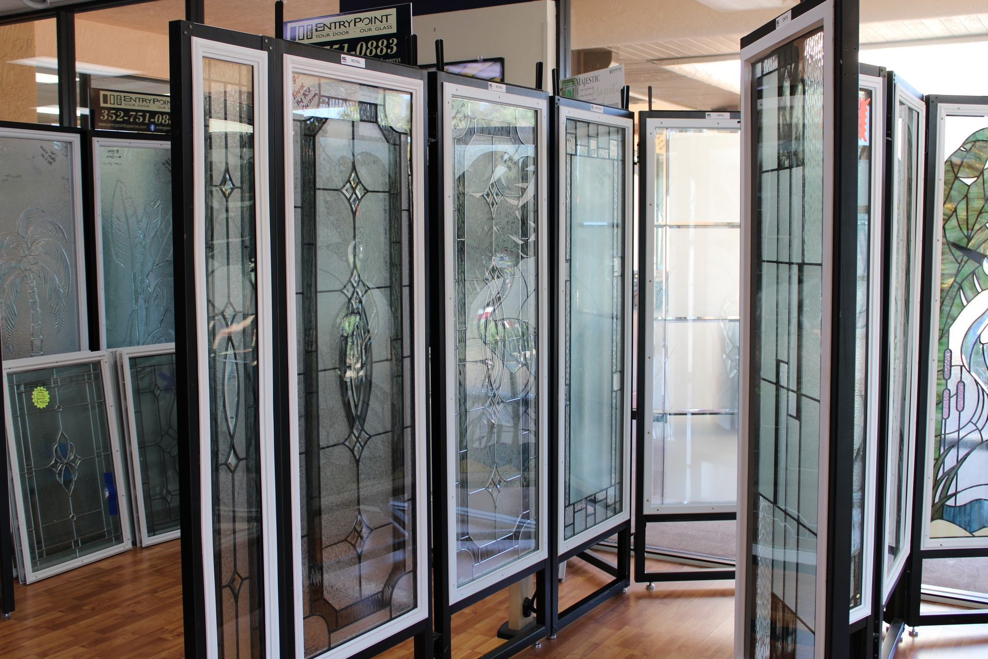 Display of glass doors with various decorative designs in a showroom setting.