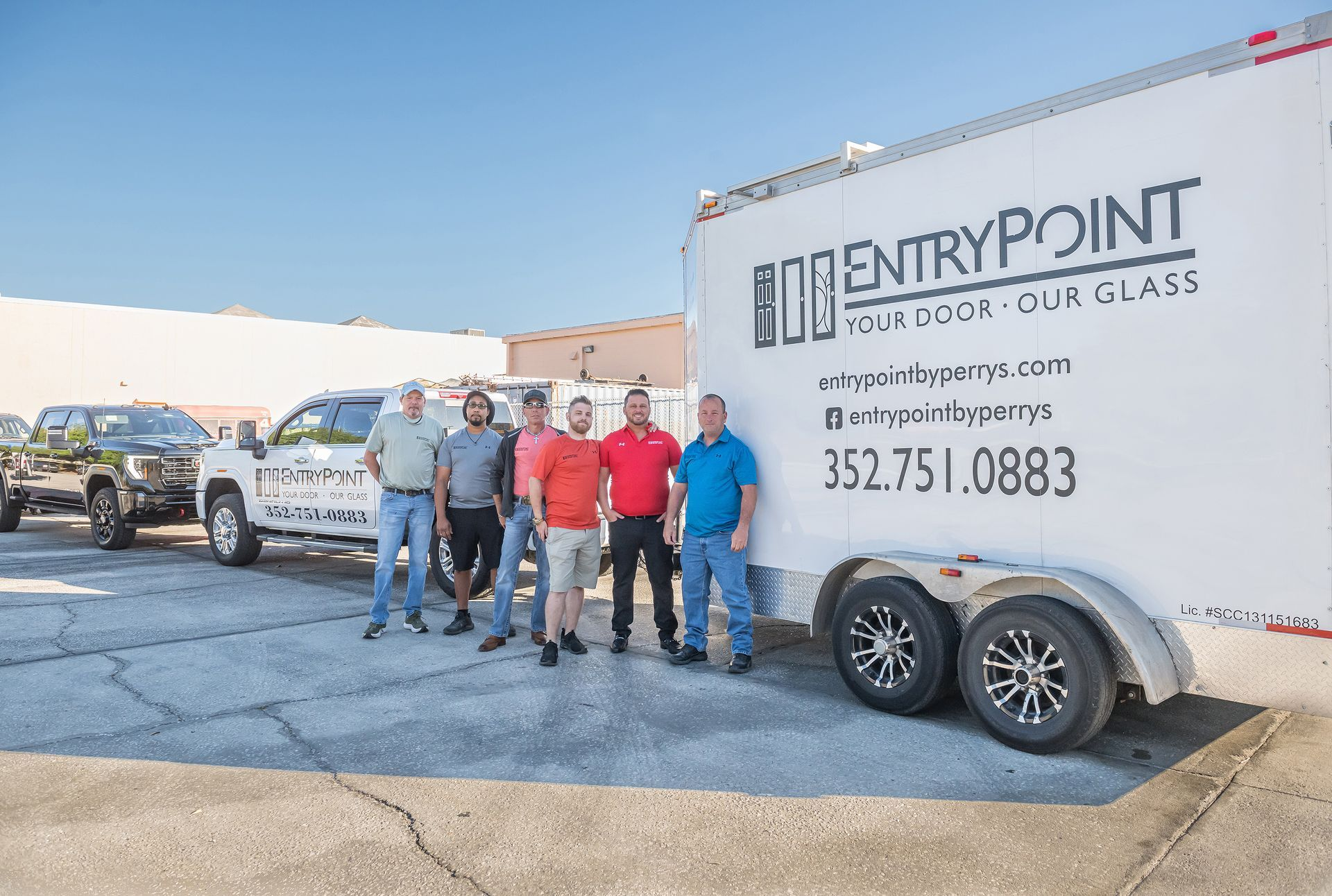 Group of men standing in front of a truck and trailer, 