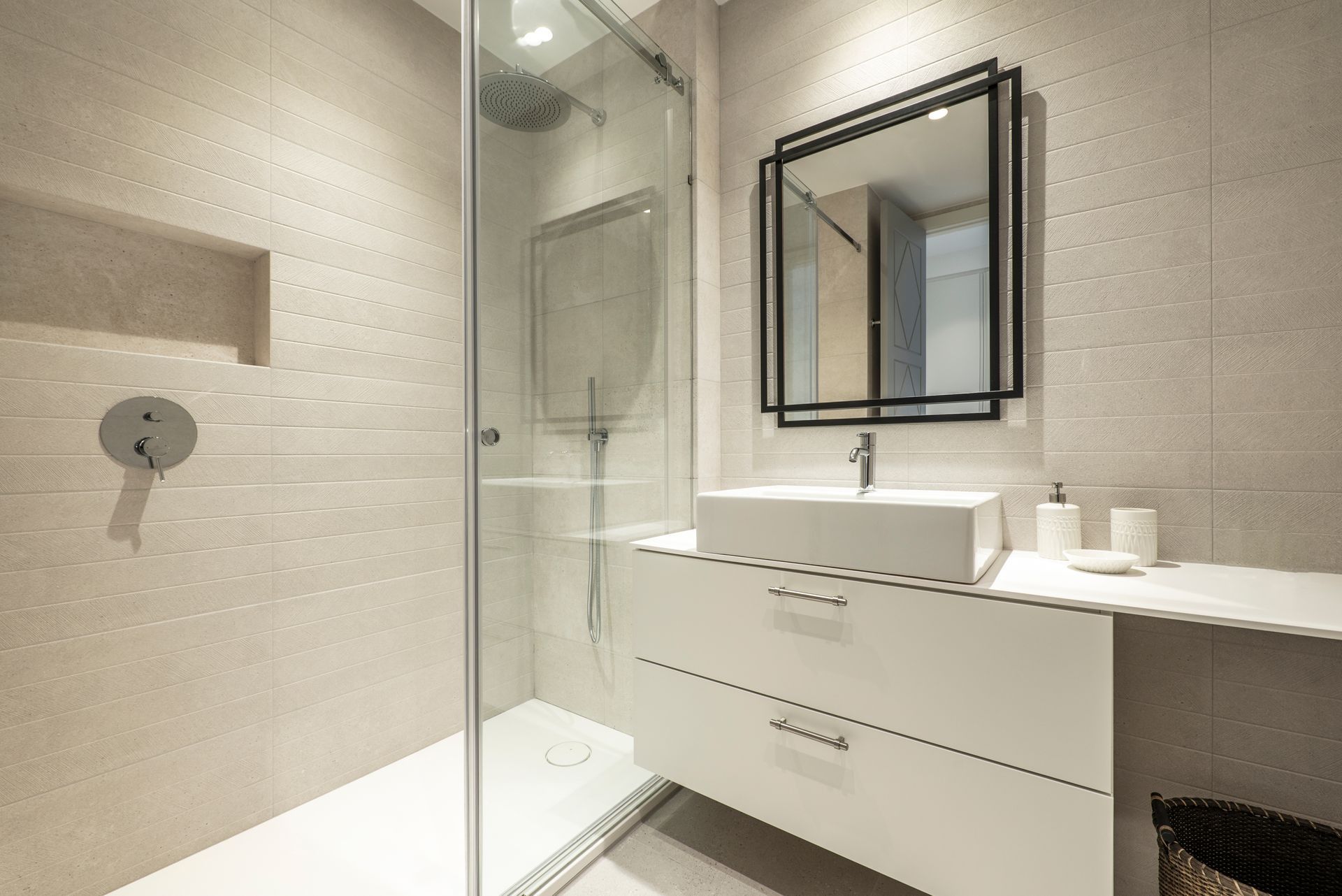 Modern bathroom with walk-in shower, white vanity, and black framed mirror.