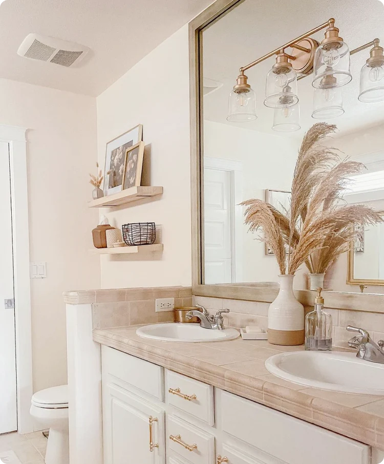 Bathroom with white vanity, tan countertop, mirror, and decorative pampas grass in a vase.