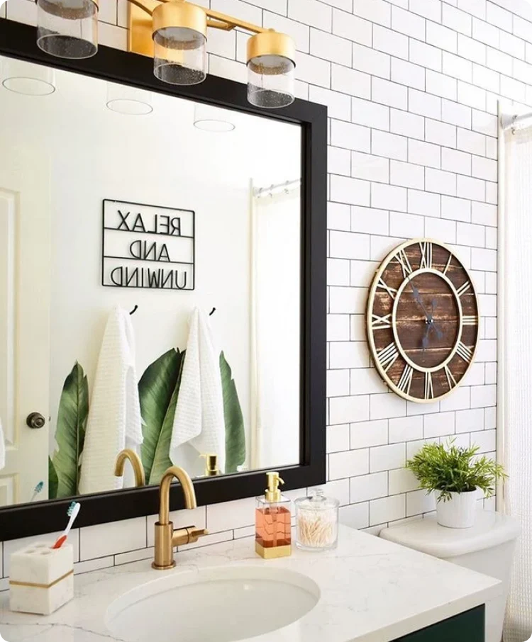 Bathroom with subway tile, gold accents, large mirror, and decorative clock.