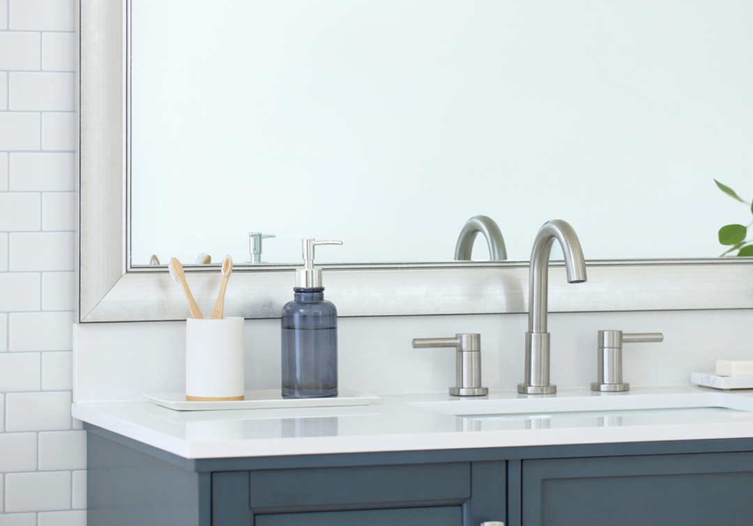 Bathroom sink with brushed nickel faucet, soap dispenser, and mirror.
