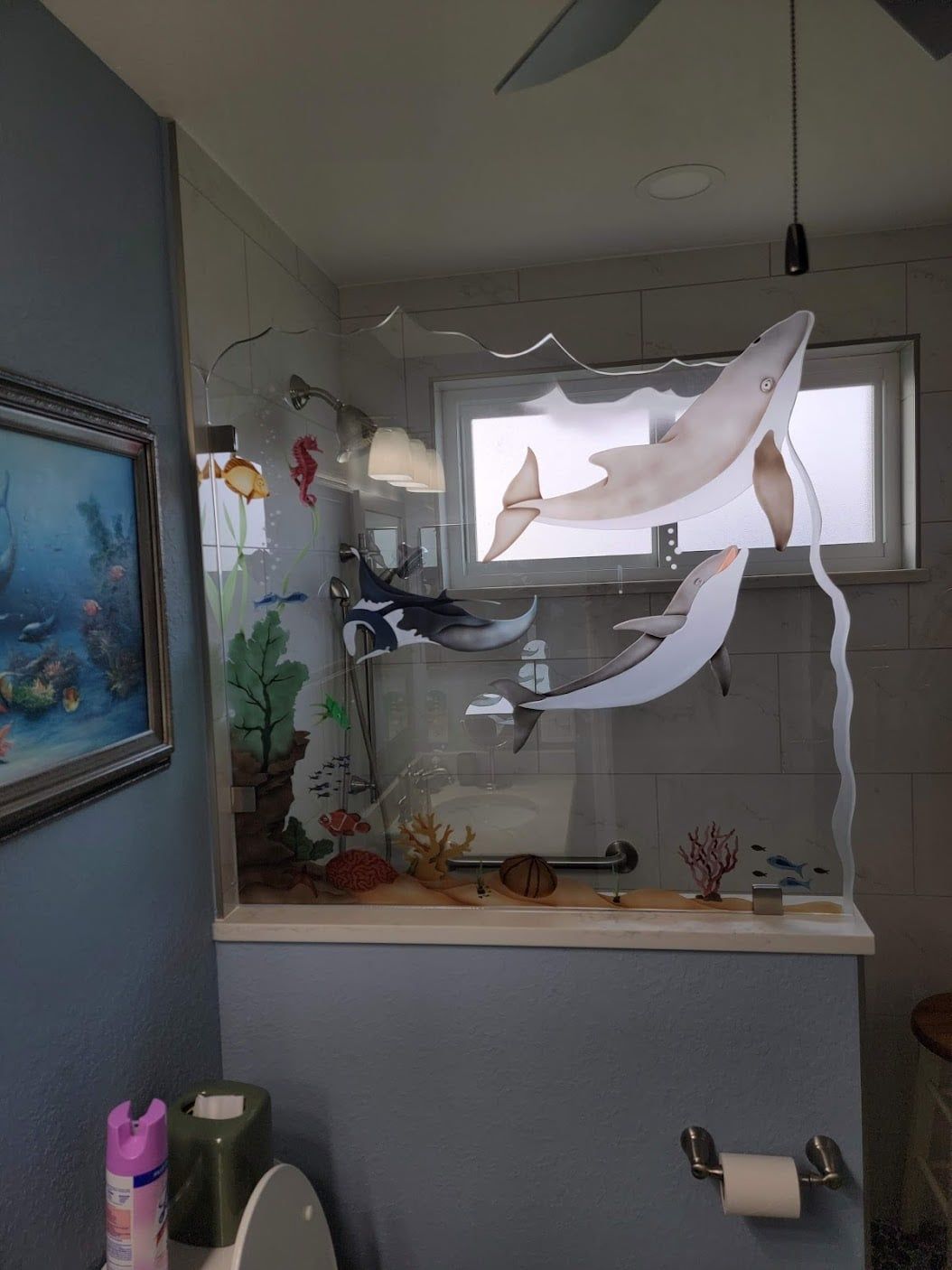 Shower with glass door, gray textured tile walls, white floor mat, and skylight.