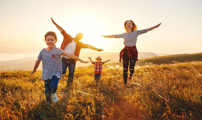 A family is running through a field at sunset.