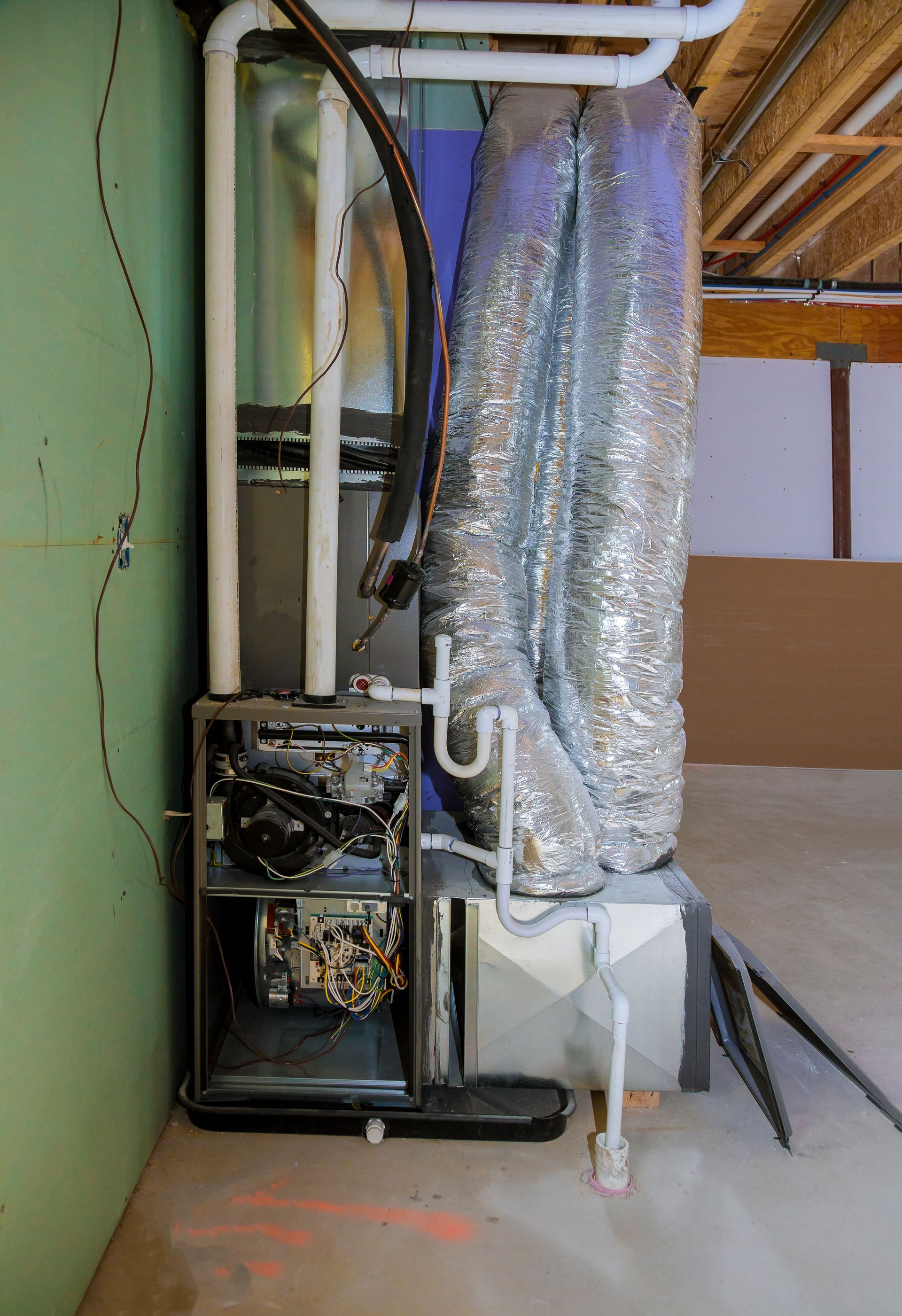 An air conditioner is sitting in the corner of a room in a basement.