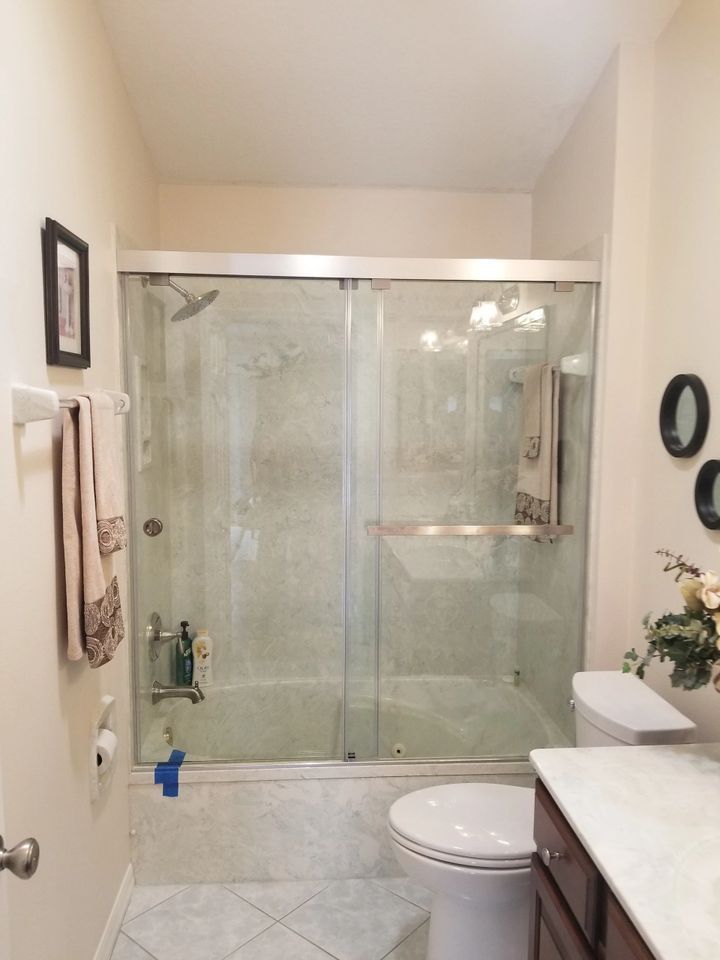 A bathroom with a toilet , sink and shower with sliding glass doors.