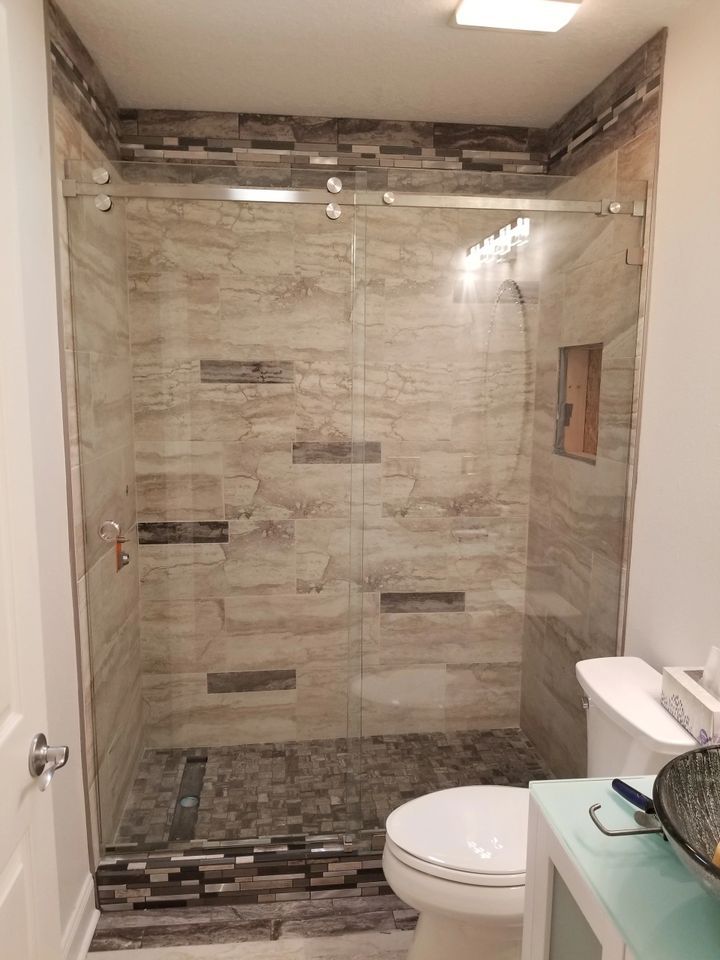 A bathroom with a walk in shower , toilet and sink.