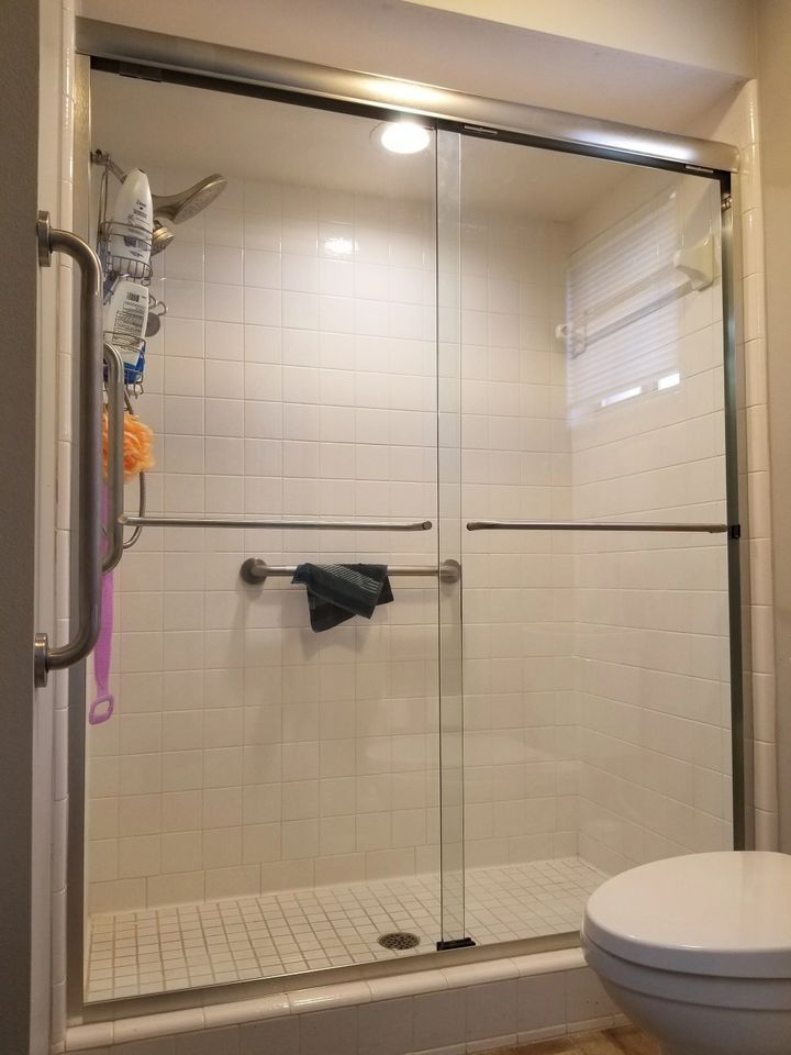 A bathroom with a sliding glass shower door and a toilet