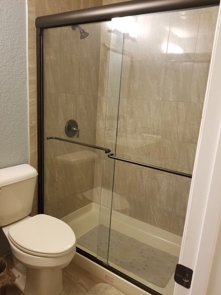 A bathroom with a toilet and a shower stall with sliding glass doors.