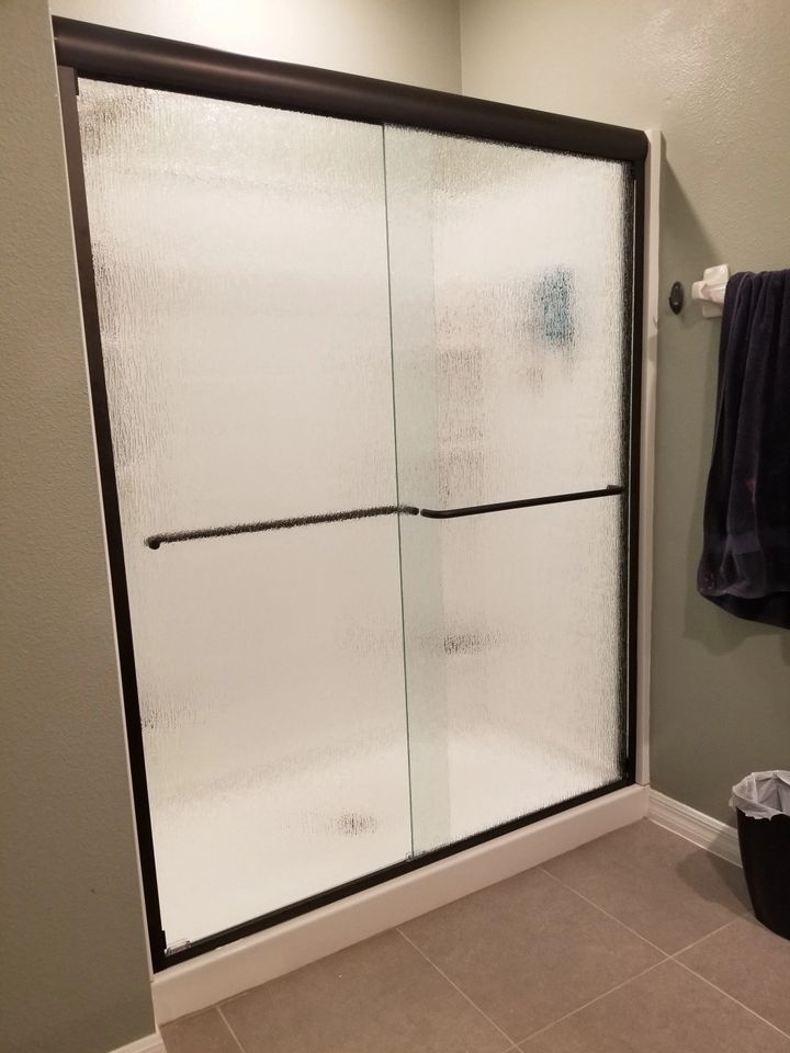 A bathroom with a sliding glass shower door and a towel rack.