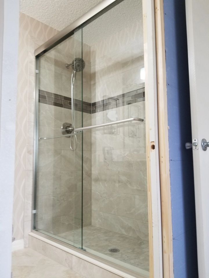 A bathroom with a sliding glass shower door and a shower head.