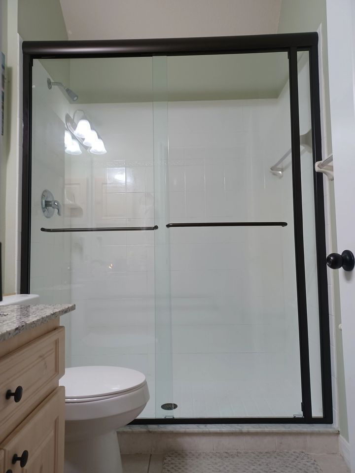 A bathroom with a toilet and a sliding glass shower door