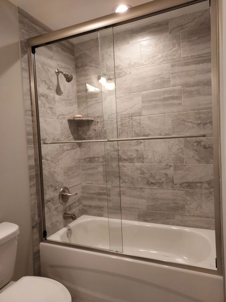 A bathroom with a bathtub , toilet , shower and sliding glass door.