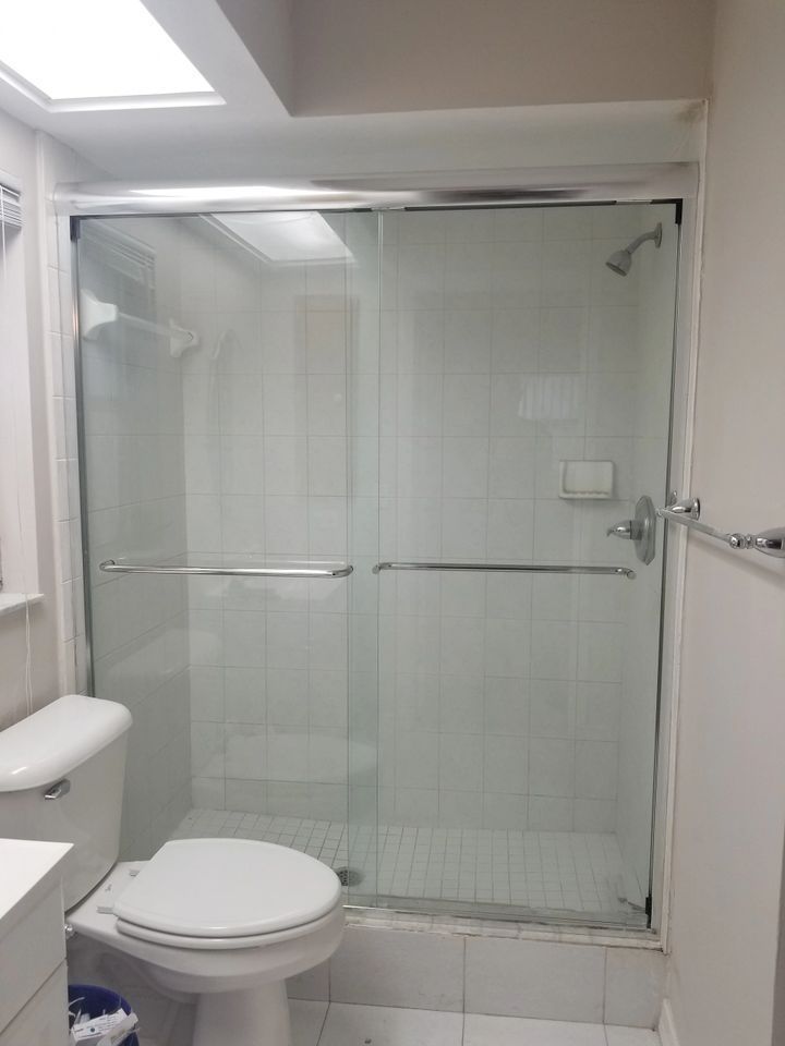 A bathroom with a toilet , sink and shower.