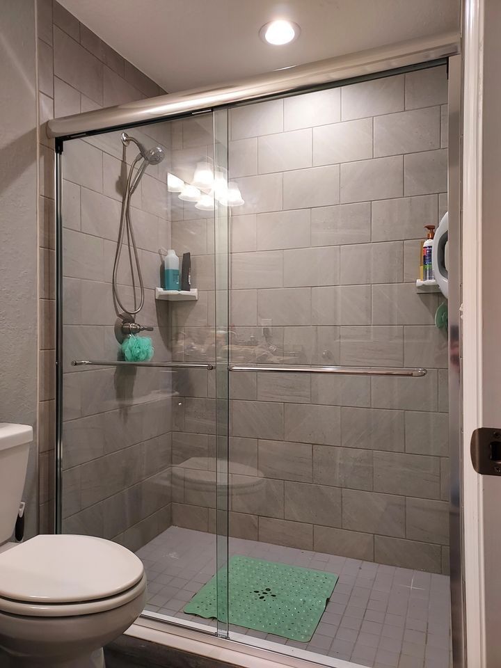 A bathroom with a toilet and a shower with sliding glass doors.