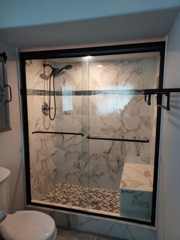 A bathroom with a toilet and a shower with sliding glass doors.